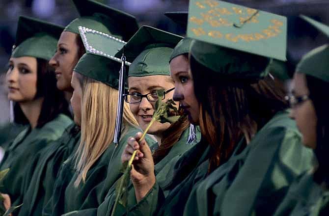 Blair Oaks senior Krista Bunch watches as fellow senior Jennifer Buschjost takes a sniff of the flower she received after accepting her diploma during Saturday's commencement ceremony for the Class of 2012.