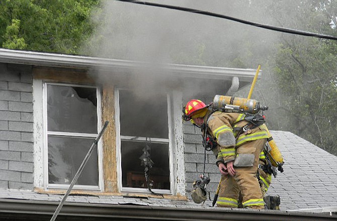 Jefferson City firefighters peer into a still smoldering upstairs room while fighting a Sunday afternoon structure fire at 415 Case Ave.