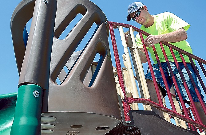 Park maintenance worker Cole Darnel removes protective packing from a piece of playground equipment in North Jefferson City Park. Employees of Jefferson City Parks and Recreation have been busy replacing an outdated children's play area and are now waiting for back-ordered rubber flooring to be delivered.