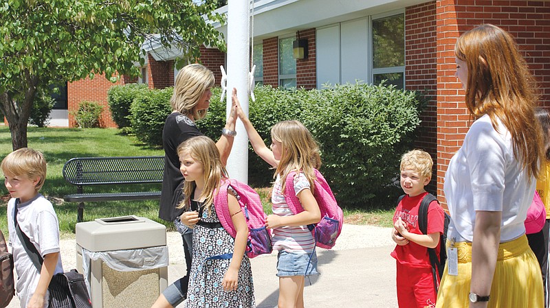 FILE: Amy Caswell hi-fives the line of bus riders goodbye as they leave Bush Elementary on the last day of school.