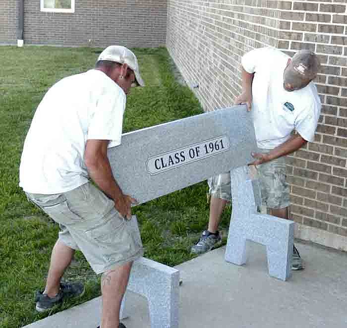 Bryan Moore and Nate Conner of Capital Monuments, Inc., install the new granite bench given to the California High School by the Class of 1961.