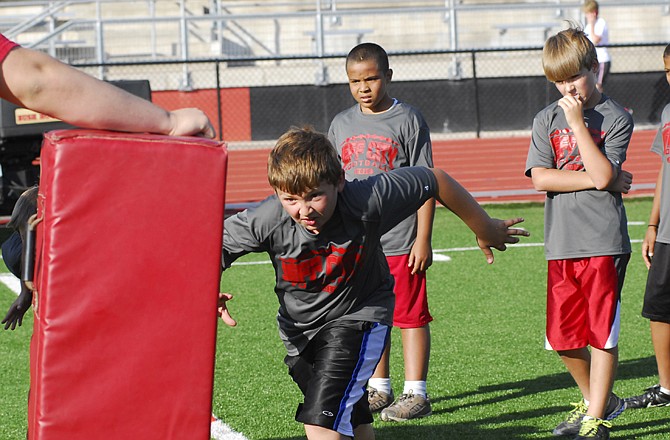 Nicholas Avey, 9, runs at a tackling dummy Wednesday during a session of the Jay football camp at Adkins Stadium.