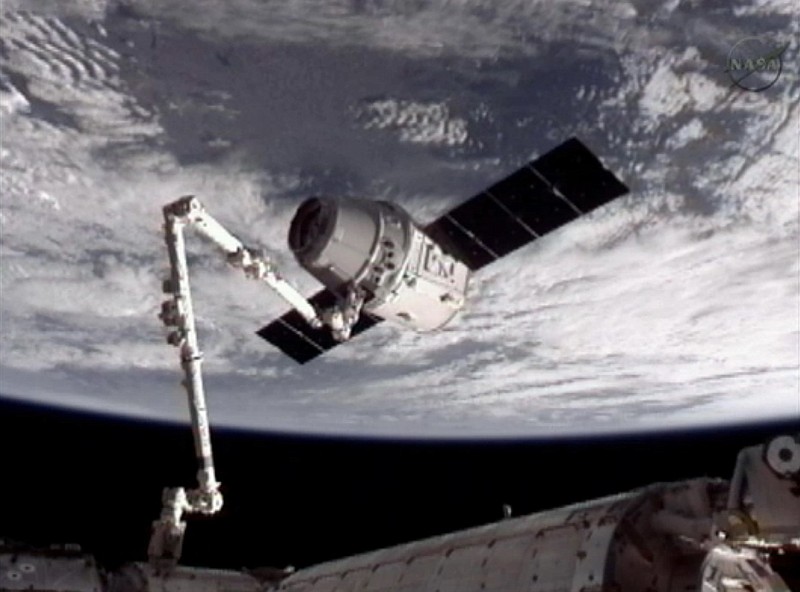 The SpaceX Dragon commercial cargo craft, top, after Dragon was grappled by the Canadarm2 robotic arm and connected to the International Space Station on Friday. Dragon is scheduled to spend about a week docked with the station before returning to Earth on May 31 for retrieval.