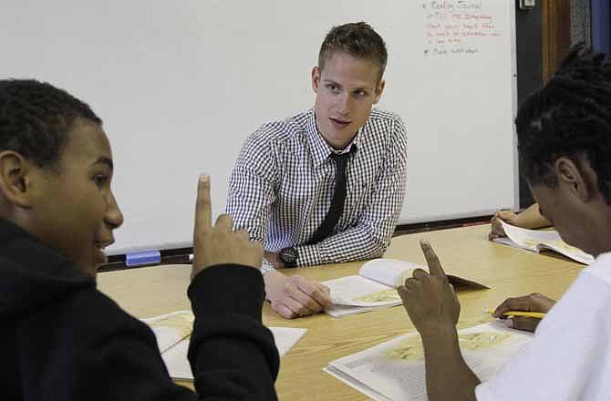 In this Monday, May 7, 2012 photo, Chad Larsen Stauber, center, a student teacher at the Lafayette School in Chicago, works with students Devion Allen, left, and Jovante Ross, on their reading skills. The 26-year-old who just received his master's degree in education knows that later in 2012, he'll have to start paying off debt of about $100,000. "This is going to be looming over my head the next 20 years," Larsen-Stauber says.