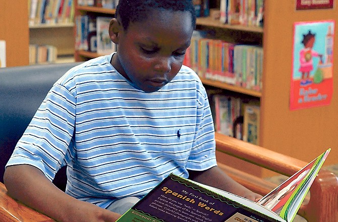 Joseph Okpodighe, 9, enjoys reading a book last week at the Missouri River Regional Library, which is sponsoring a summer reading program.