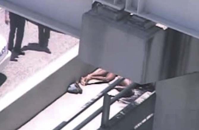 In this image taken from video, Miami police officers stand watch near a naked man, second from right, who was shot dead by a police officer when he refused to stop chewing on the face of the naked man next to him, partially obscured by a railing, on the MacArthur Causeway ramp onto Northeast 13th Street in Miami, Saturday, May 26, 2012. The victim was taken to a nearby hospital. (AP Photo/The Miami Herald)