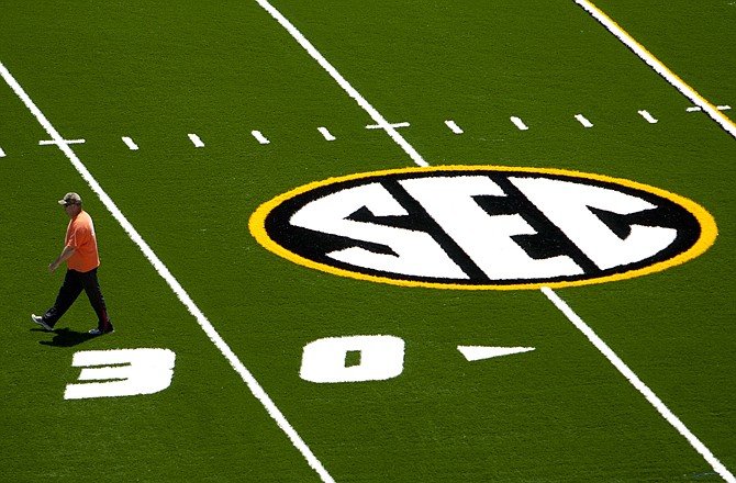 A crew member walks past the SEC logo on the new turf Wednesday on Faurot Field in Columbia. The stadium will also feature new goal posts and seating in the south end of the end zone this season, Missouri's first in the SEC.