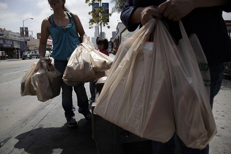 Two women wait for a bus Thursday after their grocery shopping in Los Angeles. Now that the city of Los Angeles has taken the first step toward banning plastic bags, it appears the little utilitarian bags themselves may be headed for the trash heap of history.