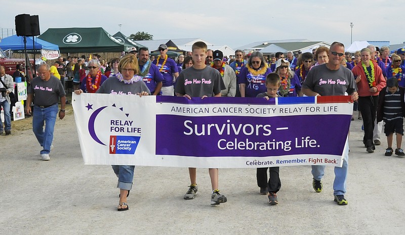 From left, Jan, Bradley, Ian and Lance MacLaughlin carry the banner on the first lap for cancer survivors Friday at the 16th annual Cole County Relay for Life held at the Jefferson City Jaycees Cole County Fairgrounds.