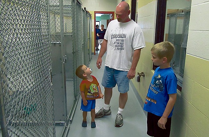 James Allen looks down to answer a question from his 2-year-old son, Owen, while 9-year-old Branden looks inside one of the pens at the new animal shelter. 