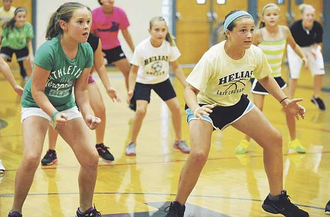 Carley Drinkard (left) and Rebecca Johanns focus on the coach as they go through drill sets Tuesday in the Helias girls basketball camp at Rackers Fieldhouse in Jefferson City. The camp will run through Thursday.