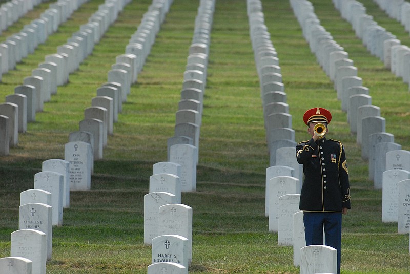 A bugler plays taps for a funeral service at Arlington National Cemetery.