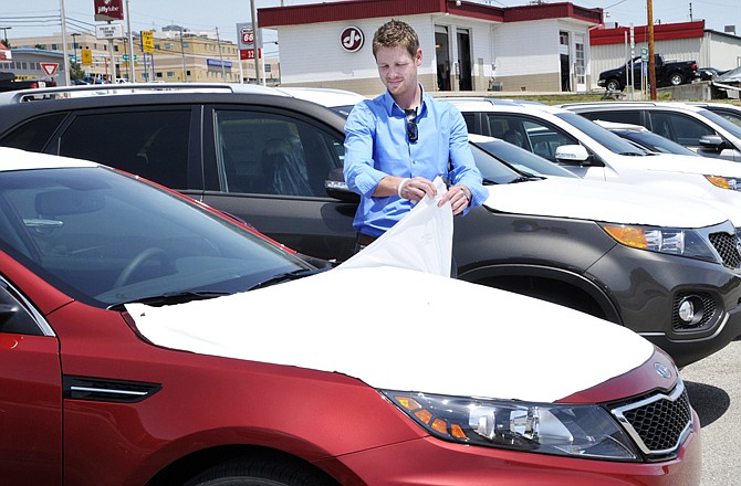Branden Baker pulls the protective transport covering from a new vehicle Thursday. Baker will be the sales manager at the new Fletcher Kia, which will open June 18 at the corner of Jefferson Street and Stadium Drive.