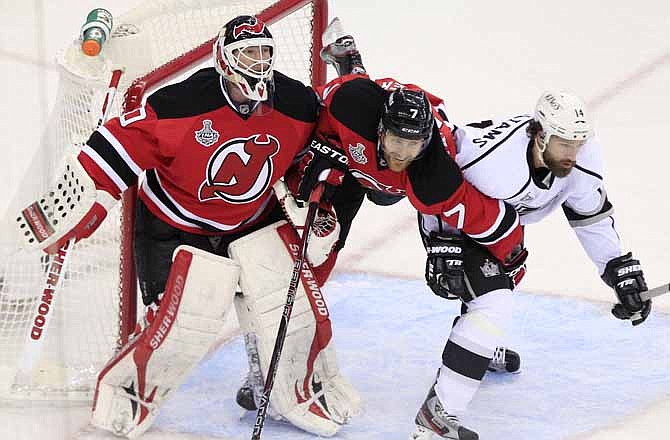 New Jersey Devils' Henrik Tallinder, center, struggles with Los Angeles Kings' Justin Williams near goalie Martin Brodeur in the second period during Game 5 of the NHL hockey Stanley Cup finals, Saturday, June 9, 2012, in Newark, N.J.