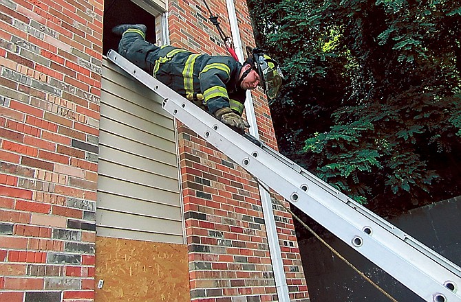 Palmyra firefighter Devin Nelson goes down a ladder during "head-first ladder bail" training at the Jefferson City Fire School on Sunday, June 10, 2012.