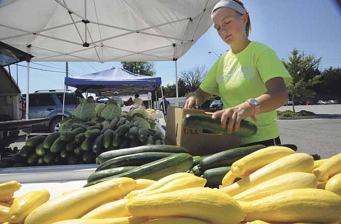 Megan Anderson puts out some zucchini Friday at the Farmer's Market in Jefferson City. Many crops have been ready early because of unseasonably warm weather earlier in the spring.