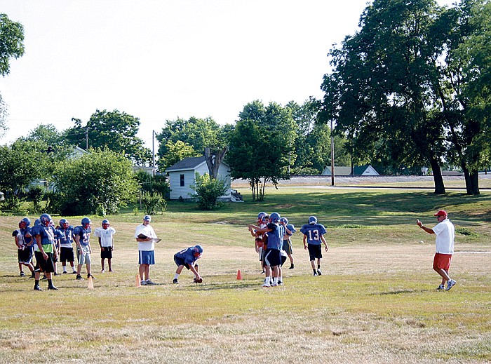 Participants of the annual California Pinto Football Camp held last week (June 4-7) at the California Middle School practice field work on passing and receiving with Coaches Marty Albertson, at right, and Rick Edwards, center, June 5. 