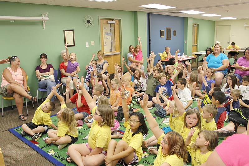Children who have pets raise their hands Wednesday as children's librarian Jerilyn Hahn read aloud from and asked questions about a book about different jobs.