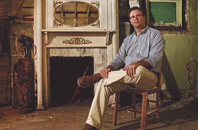 Patrick Lynn sits next to the recently relocated fireplace in the historic Clark Avenue home that he's admired since he was younger. Lynn, who purchased the stone house and two adjacent properties, has undertaken the task of rehabbing the home and restoring it to its original condition.