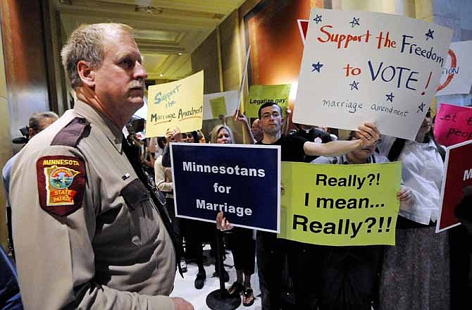 In this May 19, 2011 file photo, a state trooper stands by as demonstrators on both sides of the gay marriage issue gather outside the Minnesota House in St. Paul, Minn. 