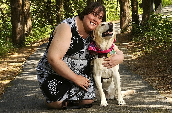 Sindy Puckett hugs her Labrador leader dog, Eleanor, along the handicap-accessible walking path at Runge Nature Center, a path the two walk often.