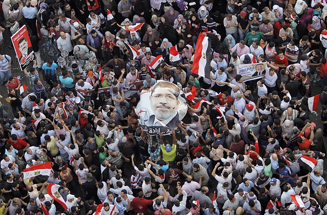 Egyptians carry a poster showing newly elected President Mohammed Morsi, in Tahrir Square, Cairo, on Sunday.