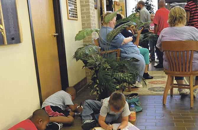 Children stay busy with books on the lobby floor outside Jefferson City Municipal Court, held in the Council Chambers at City Hall, as adults await their turn to go before the judge.
