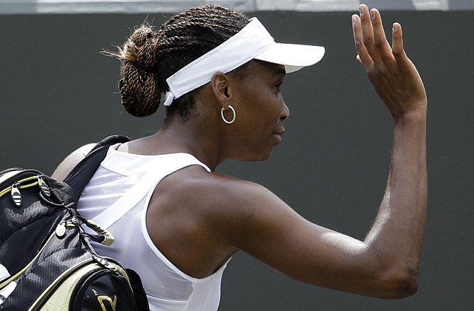Venus Williams waves to fans Monday after being defeated by Elena Vesnina during a first round women's singles match at the All England Lawn Tennis Championships at Wimbledon, England.