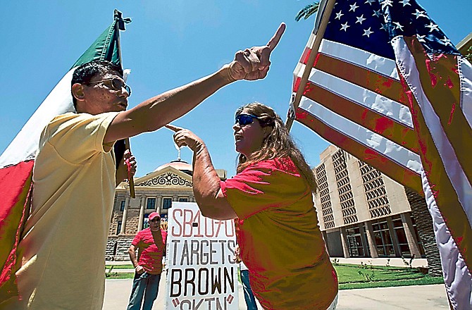 Andy Hernandez, carrying a Mexican flag, and Allison Culver, carrying an American flag argue outside the Arizona Capitol after the U.S. Supreme Court ruled most of the state's immigration law unconstitutional.