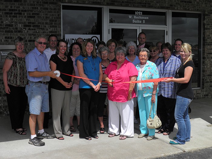 Members of the California Area Chamber of Commerce, family and friends help Carolyn Kiesling, manager of Midwest Title & Escrow, cut the ribbon on the new business located in the Village Green Shopping Center, California.