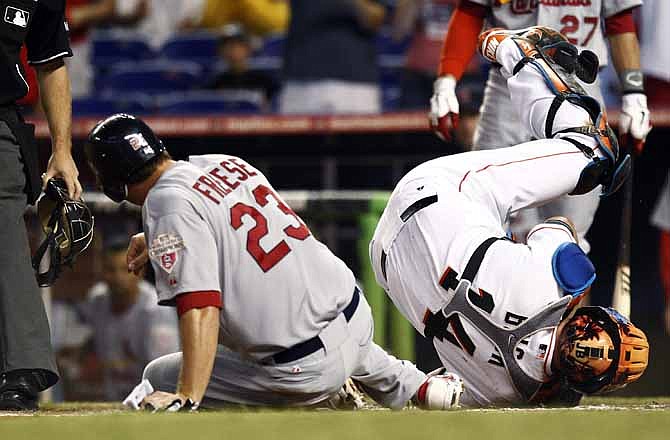 Miami Marlins catcher John Buck falls backwards after tagging St. Louis Cardinals' David Freese (32) out at home during the first inning of a baseball game in Miami, Wednesday, June 27, 2012. 