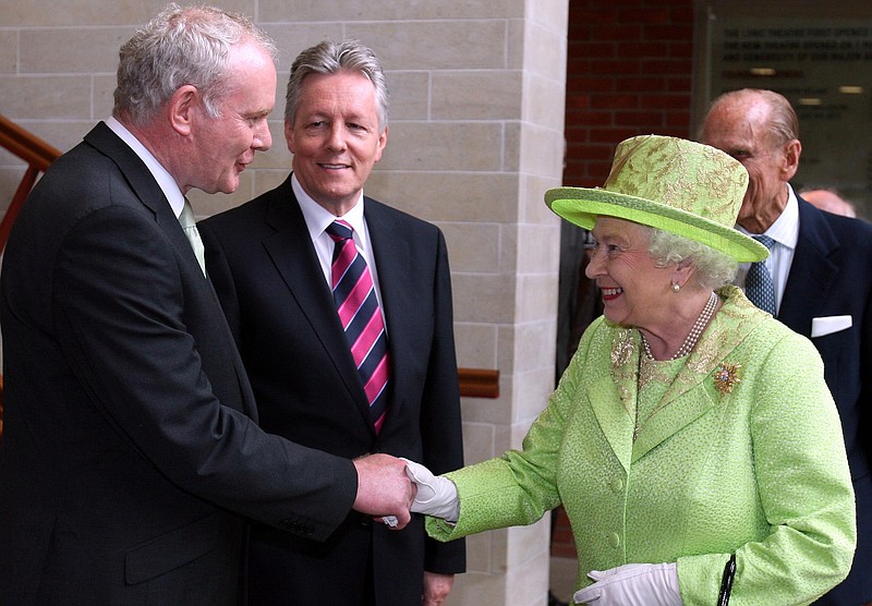 First minister Peter Robinson, center, watches Britain's Queen Elizabeth II shakes hands Wednesday with Northern Ireland Deputy First Minister and former IRA commander Martin McGuinness at the Lyric Theatre in Belfast, Northern Ireland.