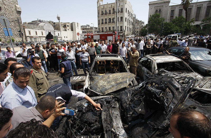 Syrians inspect burned cars at the site of a blast Thursday in the Syrian capital Damascus. A strong explosion rocked the Syrian capital near a busy market and the Palace of Justice, sending black smoke billowing into the sky.