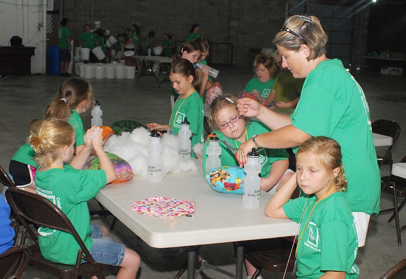 Jacki Downing helps Girl Scouts sew cushions for "sit-upon" buckets during their camp at the Jaycees Fairgrounds.