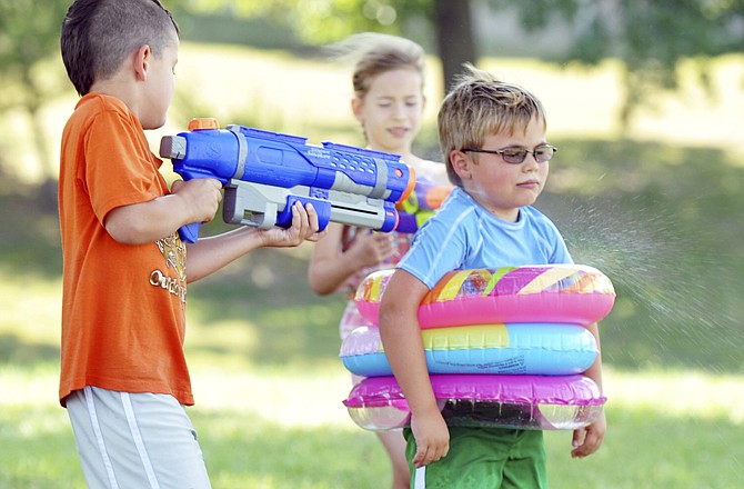 Burke Bauer steels himself as he is sprayed from two directions by Tristan Chenault, left, and Meghan Lindenbusch, in back. Several dozen students enjoyed "water day" at Sonrise Vacation Bible School on Thursday.