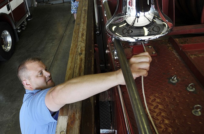 Capt. Jeff Tadsen of the Jefferson City Fire Department rings the bell atop the 1956 fire truck parked at Station No. 1 as firefighters and their families kicked off the Proposition 2 campaign.