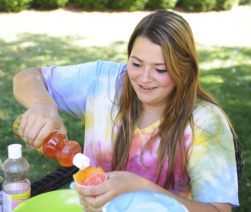 Heather Murray at 1213 Elmerine Ave. makes snow cones for the residents during activities on Elmerine Drive Wednesday morning.