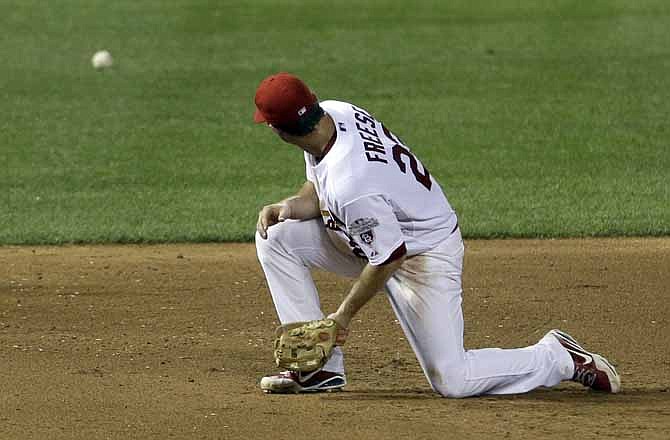 St. Louis Cardinals third baseman David Freese turns to watch a ball as it rolls past hit for a single by Miami Marlins' Carlos Lee during the sixth inning of a baseball game, Friday, July 6, 2012, in St. Louis. The Marlins' Hanley Ramirez scored and Freese was charged with an error on the play.