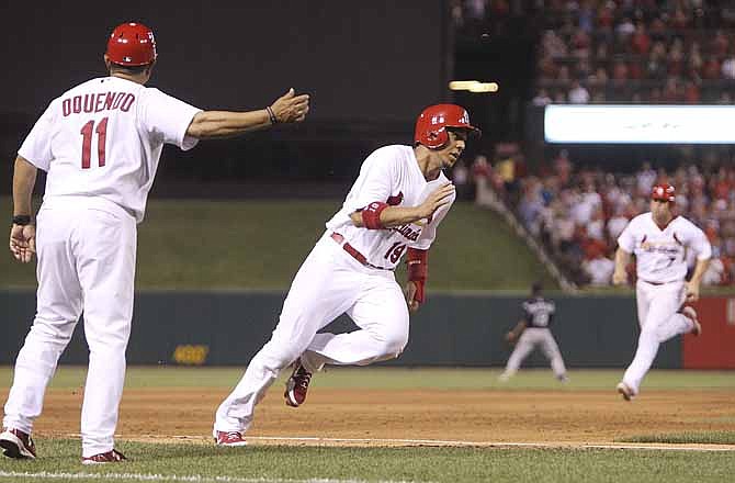 St. Cardinals' Jon Jay, center, is waved around third by third base coach Jose Oquendo as he scores on a two-run double by Carlos Beltran in the fifth inning of a baseball game against the Colorado Rockies on Thursday, July 5, 2012, in St. Louis. In the background is Matt Holliday, who advanced to third. The Cardinals won 6-2.