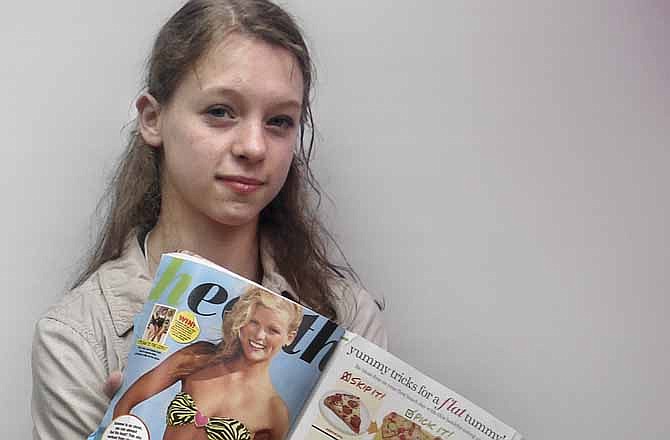 In this May 2, 2012 photo, Julia Bluhm of Waterville, Maine, holds up a copy of "Seventeen" magazine as she leads a protest outside Hearst Corp. headquarters in New York. She says images of young girls in the magazine present an impossible ideal for today's teens. 