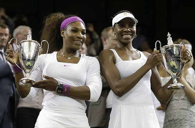 Serena Williams and Venus Williams of the United States, hold the trophy after defeating Andrea Hlavackova and Lucie Hradecka of the Czech Republic in the women's doubles final match at the All England Lawn Tennis Championships at Wimbledon, England, Saturday, July 7, 2012. 