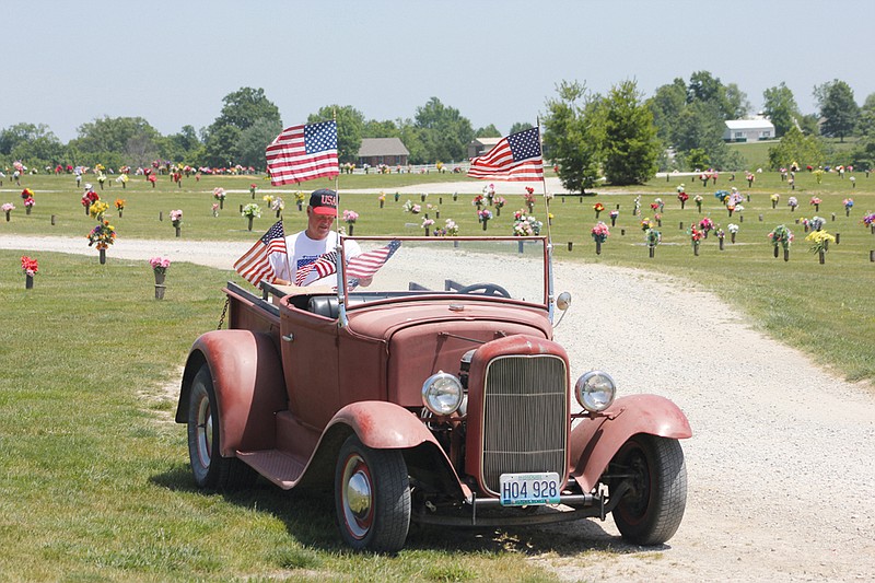 In this May 24 file photo, David Beaver returns to his car to retrieve a handful of the thousands of flags he and other volunteers placed on veterans' graves throughout the county in honor of Memorial Day. Beaver will be honored today as the first recipient of Lt. Gov. Peter Kinder's Veterans Service Award for his volunteerism in the community.