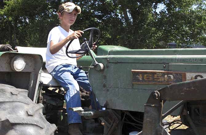 In a June 20, 2012, photo ten-year-old Jacob Mosbacher guides a tractor through a bean field on his grandparents' property near Fults, Ill. Agriculture organizations and federal lawmakers from farm states succeeded last spring in convincing the U.S. Labor Department to drop proposals limiting farm work by children such as Jacob, whose parents say such questions of safety involving kids should be left to parents. 
