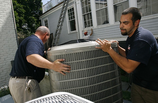 Charles Brinkley, left, and John Lerro, with Great American Heating and Air Conditioning Inc., install an air conditioner in Chevy Chase, Md.
