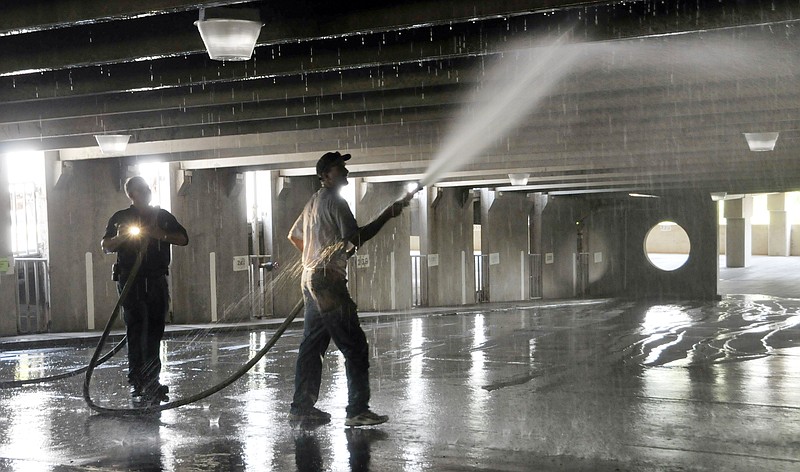 Jack Renick pulls the hose forward and back as Doug Bondurant sprays the garage ceiling, walls and floor in an effort to remove smoke residue. Crews from Facilities Management section spent much of Thursday cleaning up the aftermath of a vehicle fire in the House of Representatives parking garage, immediately west of the Capitol building. Engineers also checked the structural integrity of the concrete in the surrounding area of the fire.