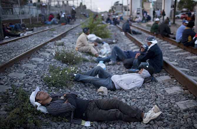 In this May 17, 2012 photo, migrants, mostly from Honduras, rest on railroad tracks as they wait for a train headed north, in Lecheria, on the outskirts of Mexico City. While the number of Mexicans heading to the U.S. has dropped dramatically, a surge of Central American migrants is making the 1,000-mile northbound journey this year, fueled in large part by the rising violence brought by the spread of Mexican drug cartels.