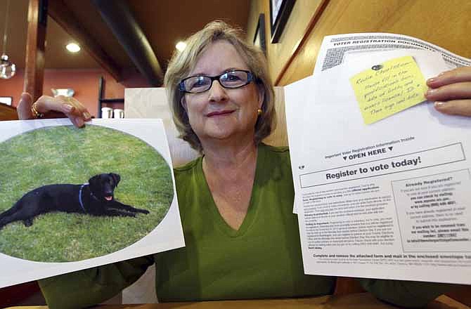 In this photo taken Wednesday, July 11, 2012, Brenda Charlston holds a photo of her long-deceased dog, Rosie, and a voter registration form for "Rosie Charlston" that arrived in the mail for the canine last month, in Seattle. Rosie was a black lab who died in 1998. A left-leaning group called the Voter Participation Center has touted the distribution of some 5 million registration forms in recent weeks, targeting Democratic voting blocs such as unmarried women, blacks, Latinos and young adults. 