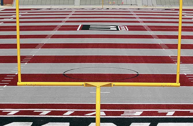 In this Thursday, July 12, 2012 photo, construction is nearly complete on the artificial turf of the football field at Lindenwood University's Belleville, Ill., campus. The university is making its leap into college football this fall and has tackled how to make its program instantly unique with the new turf of alternating maroon and gray stripes that's drawing some ridicule. 