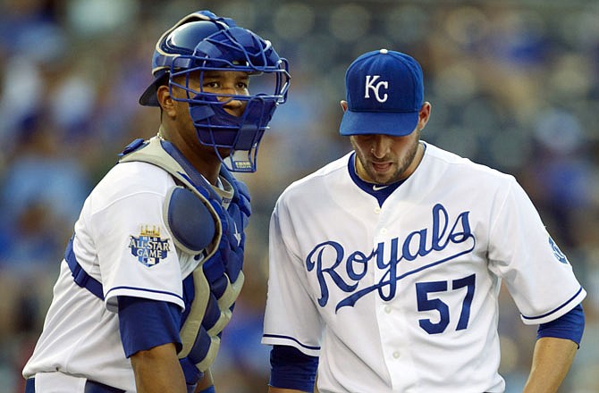 Royals starting pitcher Jonathan Sanchez (57) talks with catcher Salvador Perez during the first inning of a baseball game against the Mariners on Monday at Kauffman Stadium in Kansas City.