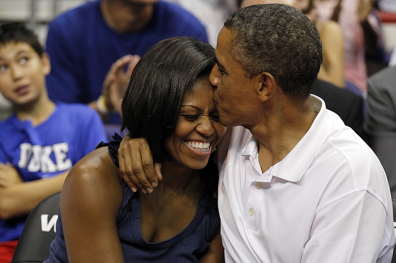 President Barack Obama kisses the head of first lady Michelle Obama, left, Monday after kissing her for "Kiss Cam" in the second half while attending the Olympic men's exhibition basketball game between Team USA and Brazil, in Washington.